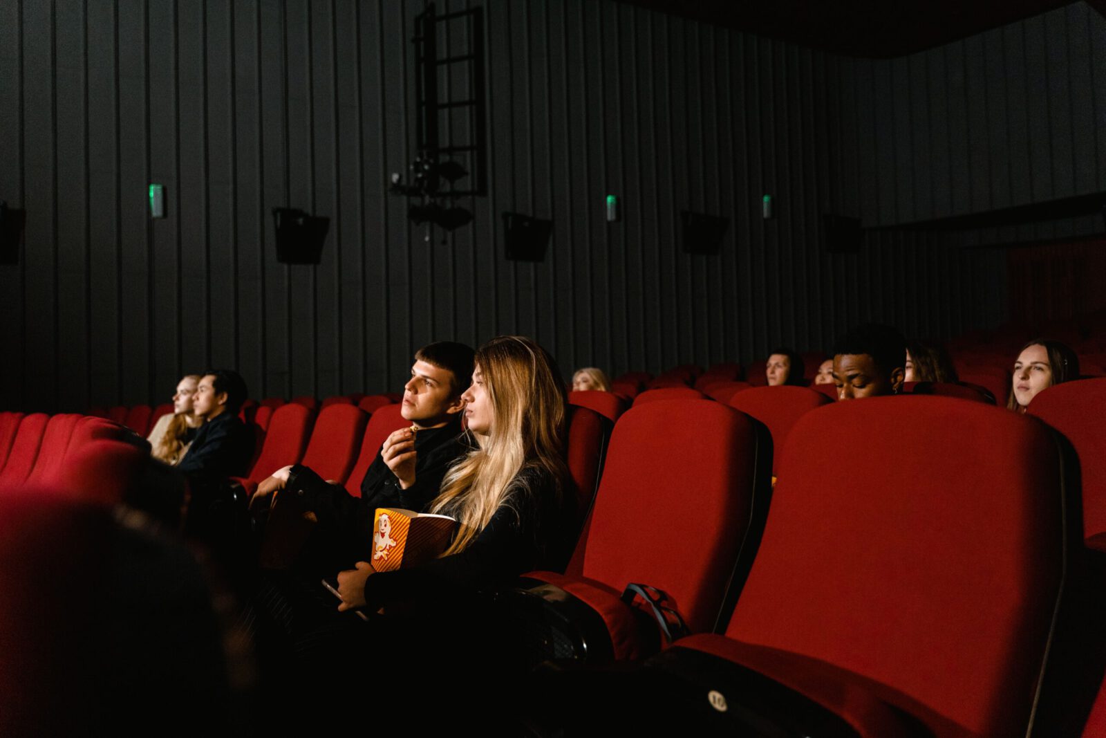 Audience enjoying a movie with popcorn in a dimly lit theater, capturing the cinematic experience.
